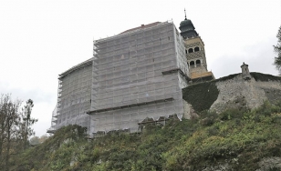 Zdjęcie przedstawia fragment zamku widziany z dołu. Zamek jest w trakcie prac renowacyjnych, jego fasada przykryta jest rusztowaniem.