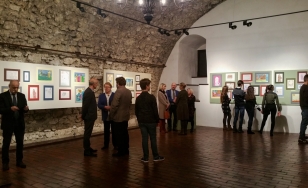 Zdjęcie przedstawia uczestników wystawy na tle ekspozycji.