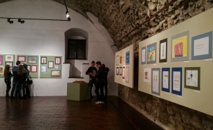 Zdjęcie przedstawia uczestników wystawy na tle ekspozycji.