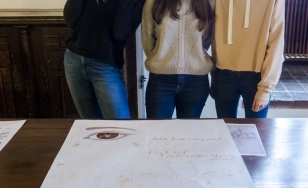 Zdjęcie uczestniczek wydarzenia z wykonaną przez siebie pracą. 3 dziewczynki pozują z projektem plakatu wykonanym techniką kolażu.