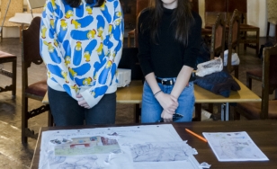 Zdjęcie uczestniczek wydarzenia z wykonaną przez siebie pracą. 2 dziewczynki pozują z projektem plakatu wykonanym techniką kolażu.