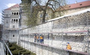 Zdjęcie przedstawia fragment zamku podczas renowacji - mur przykryty jest rusztowaniem