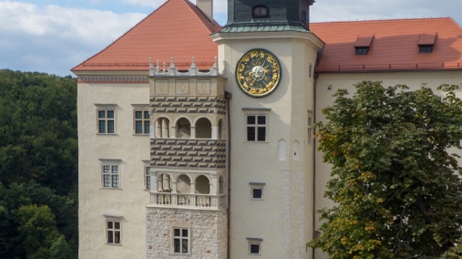 Zdjęcie przedstawia zamek z krużgankowym balkonem i wieżą zegarową.