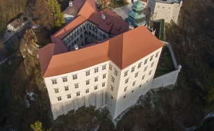 Zdjęcie przedstawia Zamek w Pieskowej Skale z lotu ptaka. Na pierwszym planie czerwone, spadziste dachy zamku.