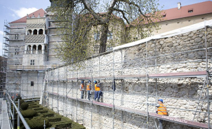 Zdjęcie przedstawia fragment zamku podczas renowacji - mur przykryty jest rusztowaniem