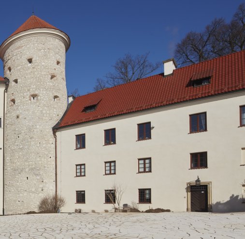 Na zdjęciu widoczny jest budynek oficyny pośrodku dwóch wież, a jego fasada porośniętą jest gęstym bluszczem.